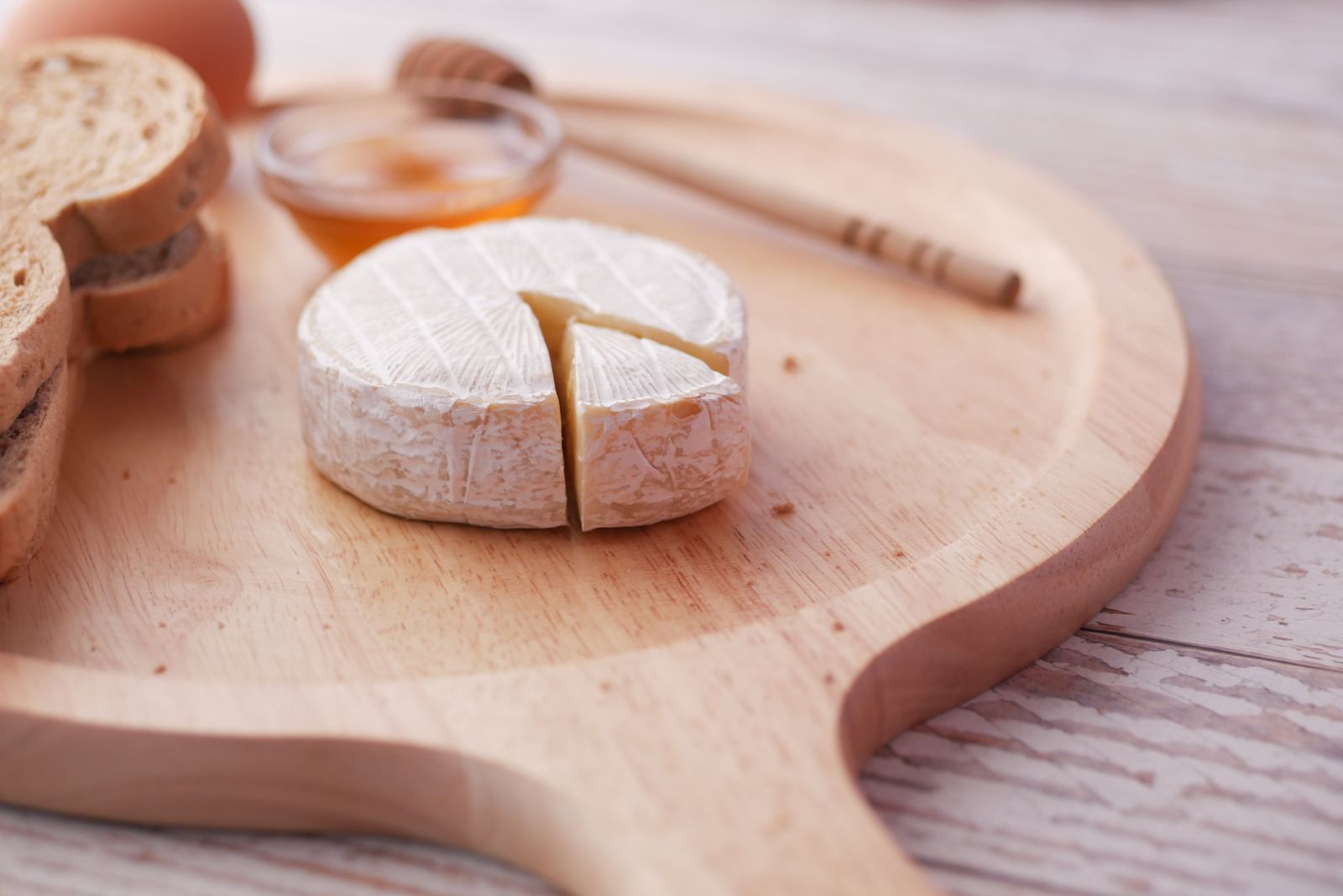 Brie cheese with honey and bread on a wooden board