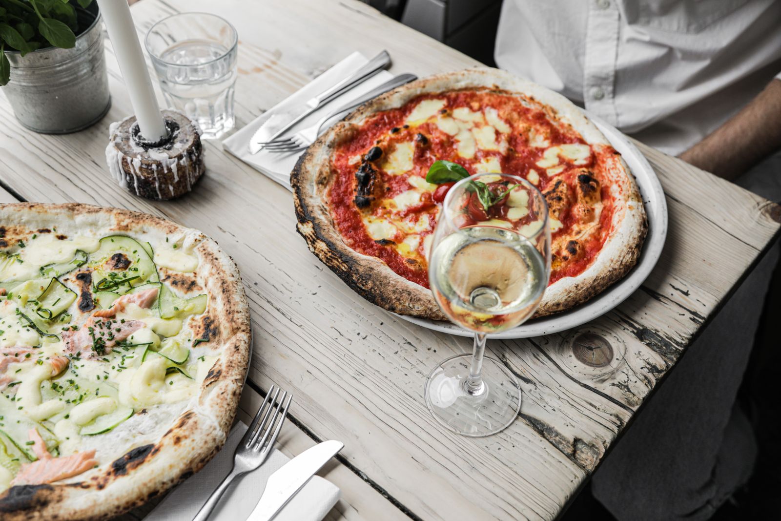 Pizzas served with white wine on a rustic table