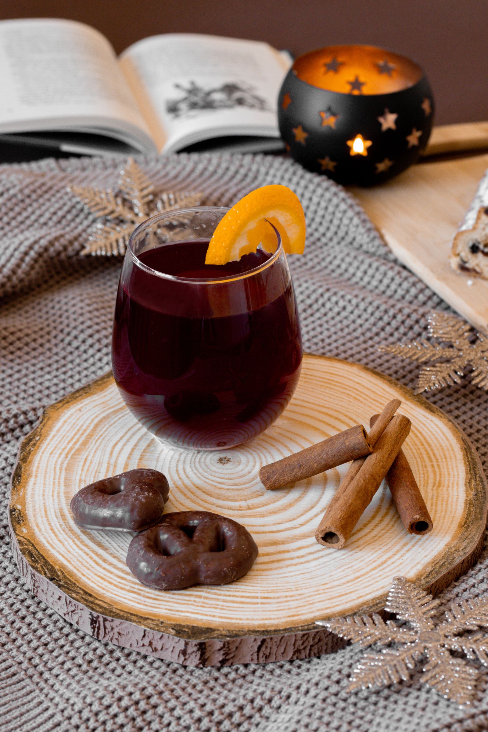 Glass of warm mulled wine with an orange slice and cinnamon sticks on a wooden tray