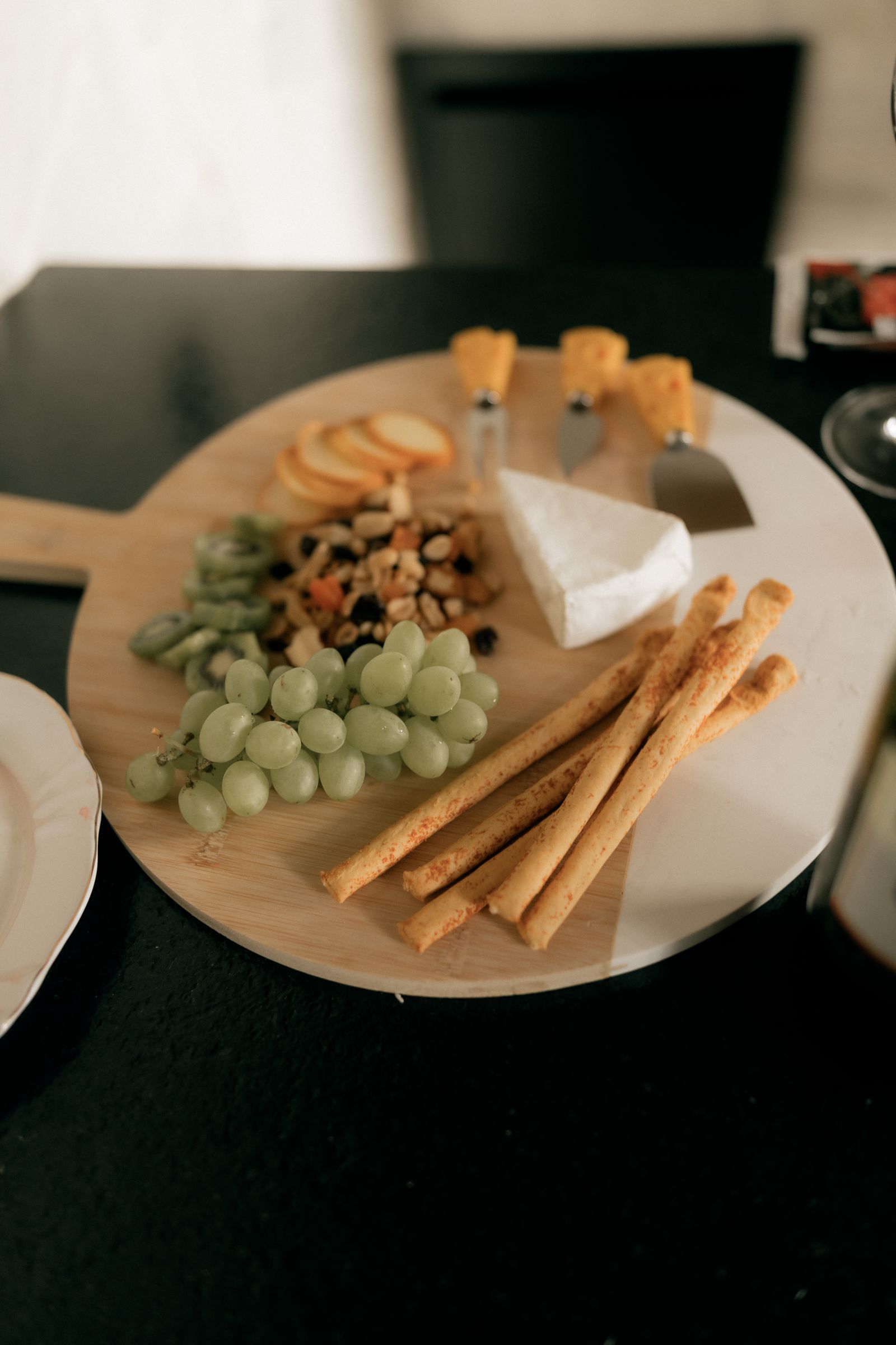 Cheese and fruit platter with nuts and crackers on a round board