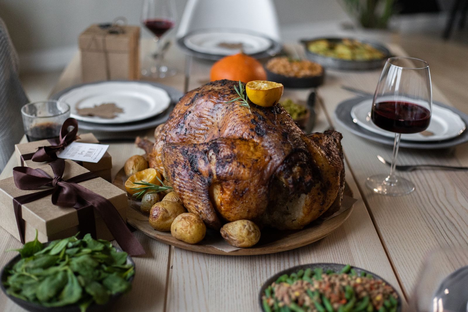 Roasted Thanksgiving turkey on a dinner table with glasses of red wine