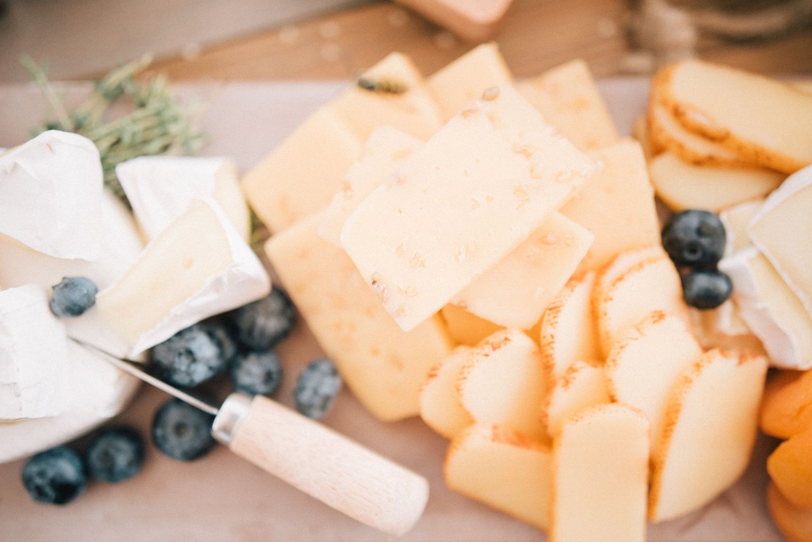Assorted wedges of cheese on a wooden board with a glass of red wine