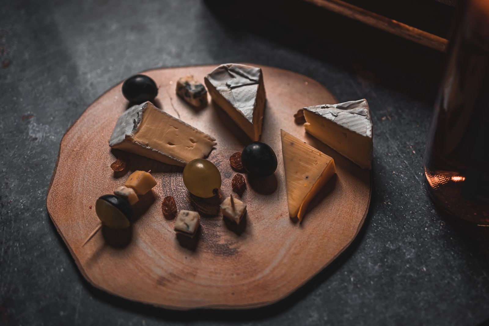 Rustic platter of assorted cheese types with nuts and grapes