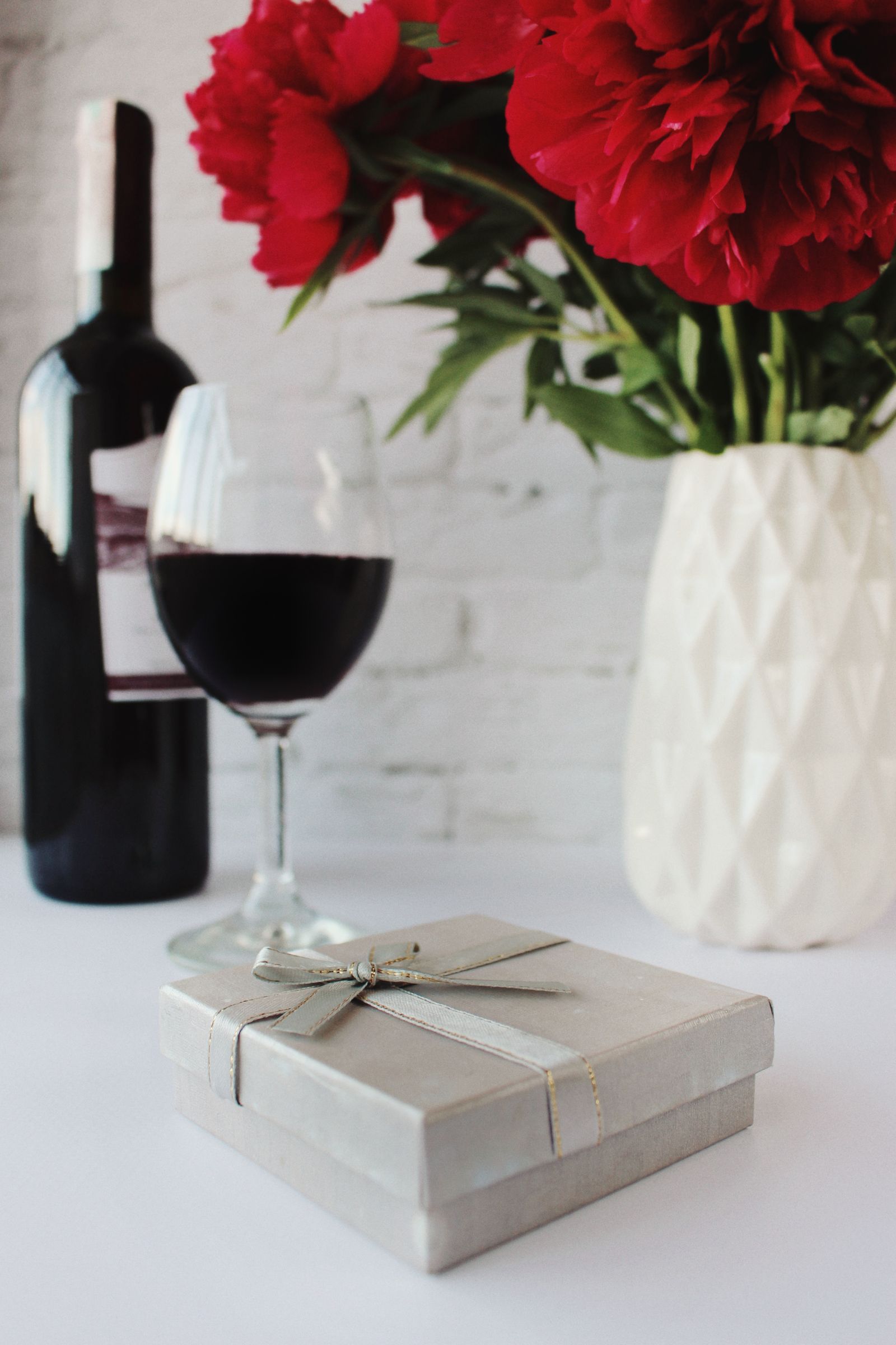 Bottle of wine with a gift box and red flowers